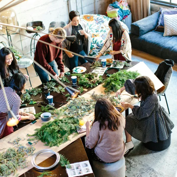 overhead photo of a group of women crafting with pine boughs during a workshop (featured image: Stella Luna holistic mental health workshops page)